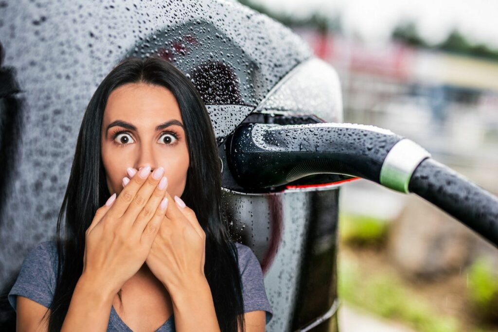 Femme surprise devant une voiture électrique sous la pluie