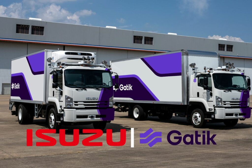 Deux camions Isuzu aux couleurs de Gatik devant un entrepôt